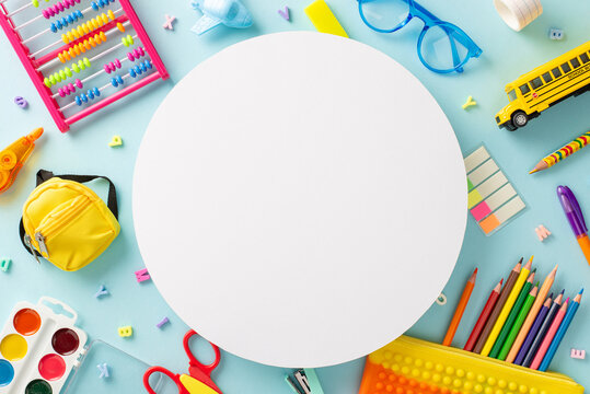 Delightful educational essentials arranged in a top view composition: a vivid assortment of colorful materials on a serene pastel blue background, providing copyspace circle for text or advertising