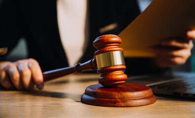 Justice and law concept.Male judge in a courtroom with the gavel, working with, computer and docking keyboard, eyeglasses, on table in morning light