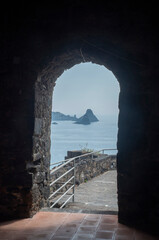 View from arched stone door in Norman castle Aci Castello to small rocky islands near Catania, Sicilia, Italy,