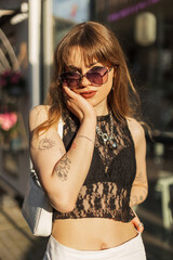 Beautiful fashionable hipster woman model with vintage sunglasses in trendy fashion summer clothes...