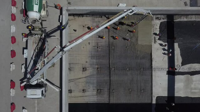 Workers filling concrete on the ground, construction of a highway tunnel. Aerial view with drone.