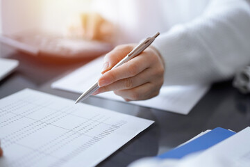 Woman accountant using a calculator and laptop computer while counting taxes for a client. Business...