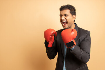Mental health, Chronic stress, Angry young indian employee wearing boxing gloves punching isolated...