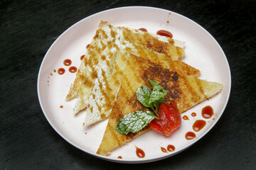 Crepes drenched in chocolate syrup with fresh strawberries and mint leaf