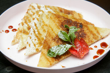 Crepes drenched in chocolate syrup with fresh strawberries and mint leaf