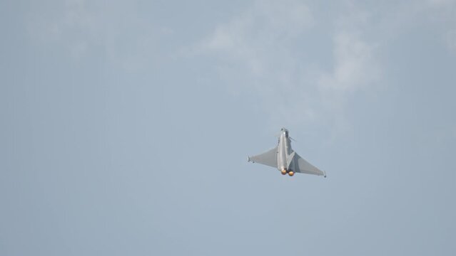 Fast fighter jet during high speed combat maneuvers with clouds