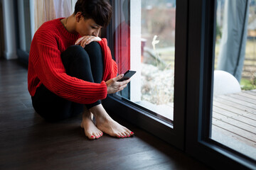 Unhappy depressed woman reading messages on her smartphone
