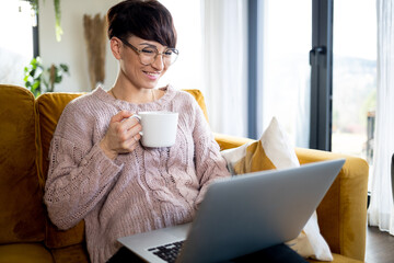 Smiling woman doing video call using laptop at home