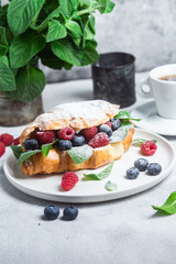 Croissant with raspberries, blueberries and cream cheese on a white plate