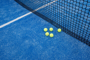 blue paddle tennis court with five balls near the net