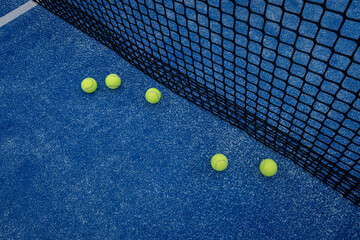 blue paddle tennis court with five balls near the net