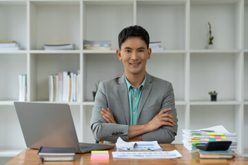 Handsome Asian businessman in gray suit with crossed arms feeling confident, smart, leadership...