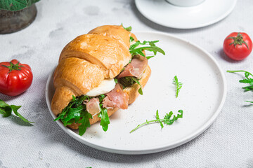 Croissant with jamon, mozzarella and arugula on a plate