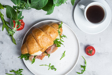 Croissant with jamon, mozzarella and arugula on a plate