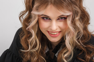 young girl in black school dress poses as doll on white background in studio