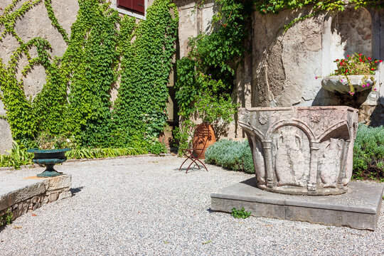 The courtyard of the Duino Castle with an ancient fountain and flower bed.  Duino, Italy.