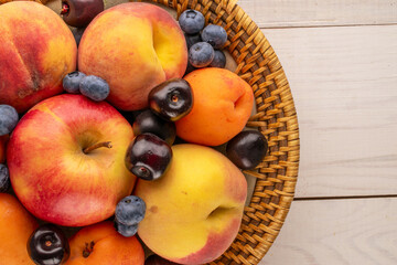 Naklejka na ściany i meble Fresh sweet fruits in a ceramic plate on a wooden table, macro, top view.