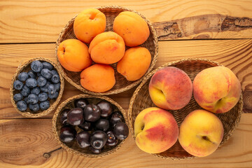 Fresh sweet fruits in straw plates on wooden table, macro, top view.