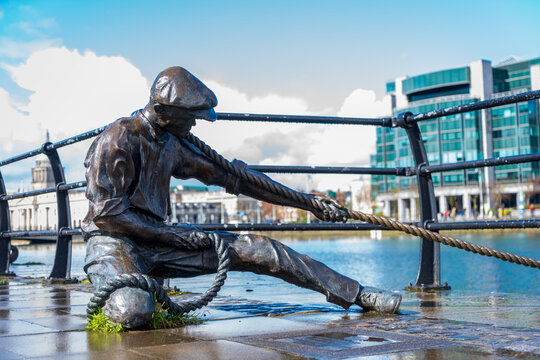 The Leinesman (a docker in a flat cap pulling a ship's rope) bronze sculpture by Irish artist Dony, tribute, remember, MacManus on Dublin's Liffey Quay Dublin, Ireland 