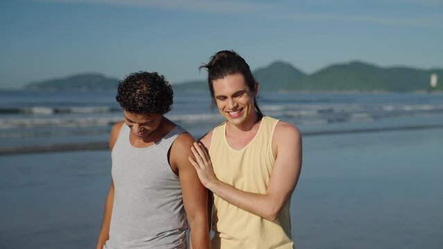 An LGBTQ couple have a romantic moment walking on the beach with each other. 
