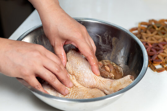 Marinating chicken with hand in an aluminum bowl 