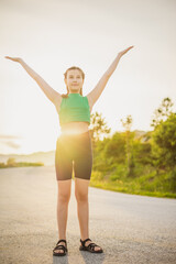 Obraz premium vertical portrait cute girl in tracksuit is engaged in sports activities on road surrounded by nature