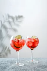 Fotobehang Campari and Tonic. Classic alcoholic cocktail drink with red bitter. Alcohol drink with lime. Campari and Tonic cocktail with lime. © svetlana_nsk