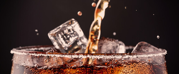 Fototapeta na wymiar Pouring of Cola and Ice. Cola soda and ice splashing fizzing or floating up to top of surface. Close up of ice in cola water. Texture of carbonate drink with bubbles in glass. Cold drink background