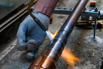 worker welds copper pipes with a gas torch