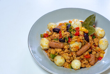 Ground chicken meat dish with quail egg, mini sausage, and other vegetable ingredients. 