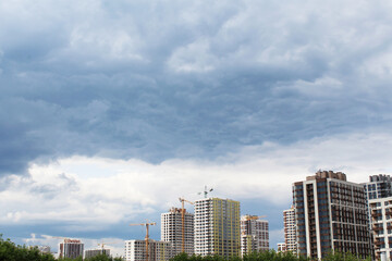 Fototapeta na wymiar storm clouds over a city with modern new houses and houses under construction, city skyline, sky and clouds