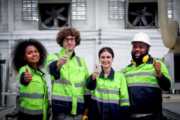 Obraz premium Multi-ethnic group of industrial women men worker team wearing helmet and safety vest, standing giving thumbs up at CNC woodworking carpentry furniture factory. Teamwork unity diversity in workplace.