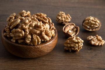 Fototapeta na wymiar Peeled walnuts and whole walnuts in wooden bowl,top view 