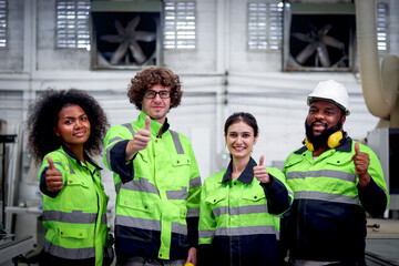 Multi-ethnic group of industrial women men worker team wearing helmet and safety vest, standing giving thumbs up at CNC woodworking carpentry furniture factory. Teamwork unity diversity in workplace.