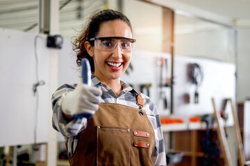 Portrait of happy smiling beautiful carpenter woman wearing safety glasses goggles and apron,...