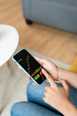 Woman holding mobile phone with stock market shares on screen.