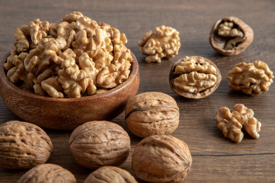 Peeled walnuts and whole walnuts in wooden bowl,top view