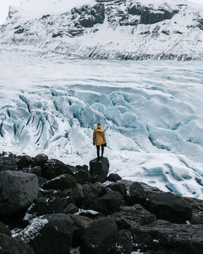 man on the top of a rock overlooking a glacier in iceland
