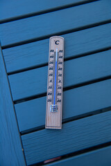 Analog thermometer showing temperature on a table in a backyard during a heat wave.