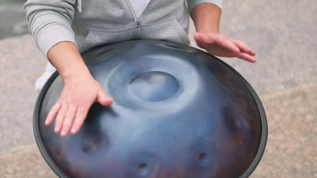 Hands with hang drum close up man practicing native music traditional drumming instrument played with hands. near water relaxing sound performance