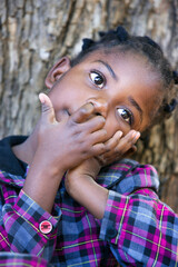 african girl with braids piking her nose in the garden