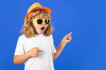 Young handsome child boy pointing away on blue background. Excited kid boy on studio isolated background. Surprised face, amazed emotions of child.