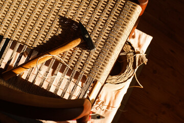 A carpenter weaving a new seat for a vintage danish chair with paper cord handcraft in a workshop