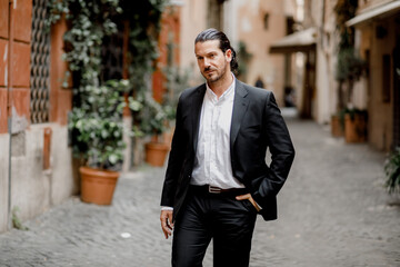 A handsome brunette Spaniard in a classic suit walks through the city
