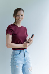 Fototapeta premium Young and attractive woman smiling at the camera, looking professional and ready to do business with a white background. Wearing a T shirt, holding document.