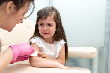 A doctor injects a vaccine to a little girl. The girl is afraid and crying.