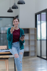 Sharing good business news. Attractive young businesswoman talking on the mobile phone and smiling while sitting at her working place in office and looking at laptop PC