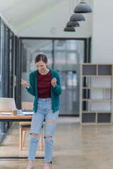 Sharing good business news. Attractive young businesswoman talking on the mobile phone and smiling while sitting at her working place in office and looking at laptop PC