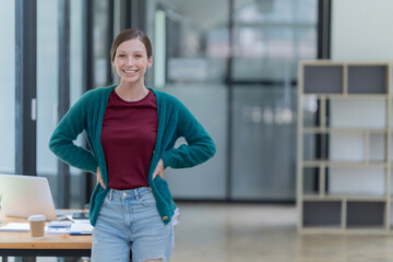 Obraz premium Sharing good business news. Attractive young businesswoman talking on the mobile phone and smiling while sitting at her working place in office and looking at laptop PC