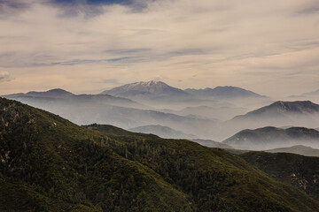 Clouds rolling into the mountains with a green forest